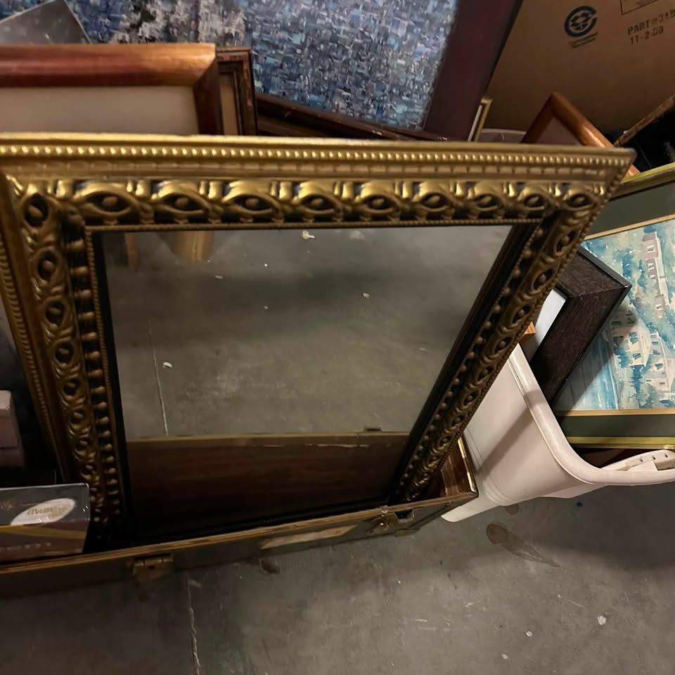 Ornate gold picture frame and stacked artwork from an estate